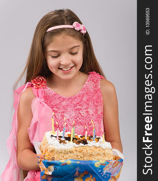 Girl in a pink dress with a cake in hand blowing the candles. Girl in a pink dress with a cake in hand blowing the candles