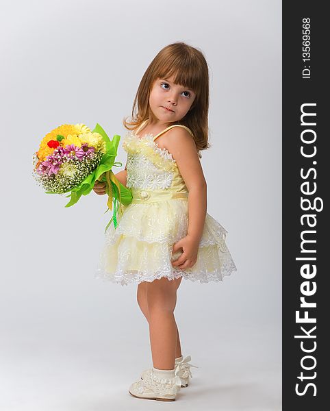 Little beauty in a white dress with a bouquet of flowers in their hands