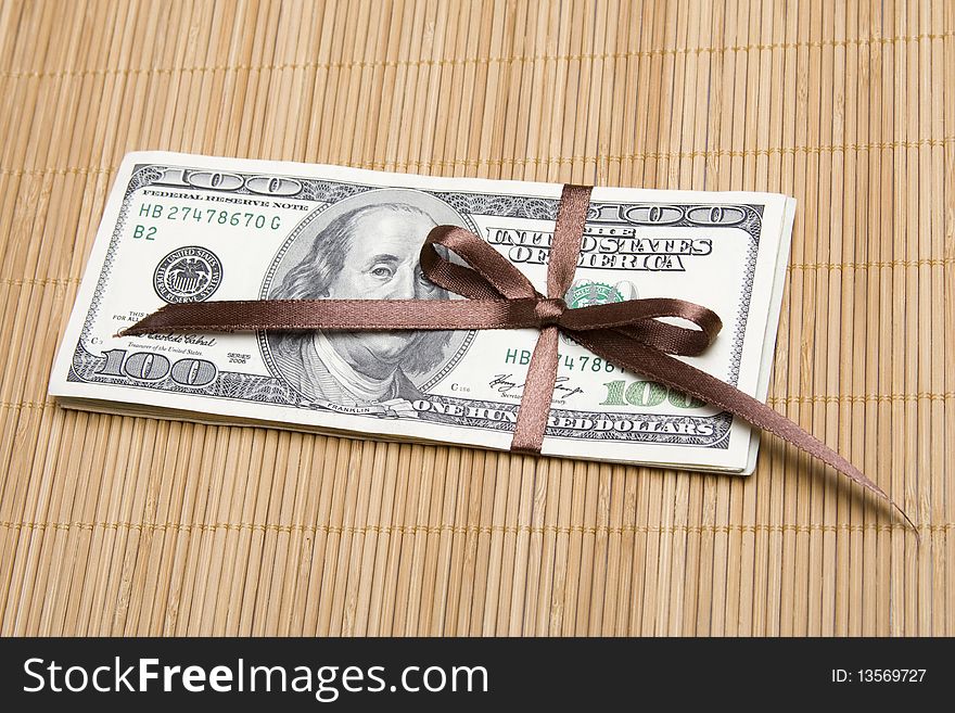 Stack of money wrapped in brown bow and ribbon. Stack of money wrapped in brown bow and ribbon