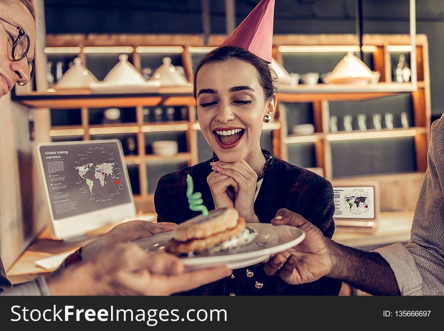 Feeling happiness. Cheerful brunette girl holding hands under chin while looking at burger. Feeling happiness. Cheerful brunette girl holding hands under chin while looking at burger
