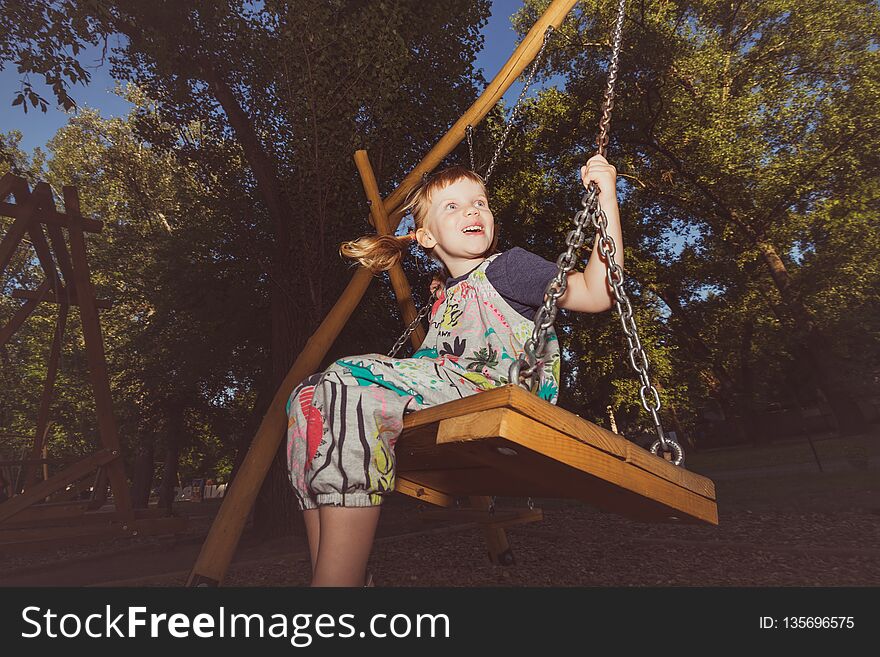 Little Girl Is Having Fun On A Swing In City Park