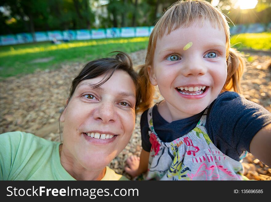 Funny little girl with her happy mother are taking selfie