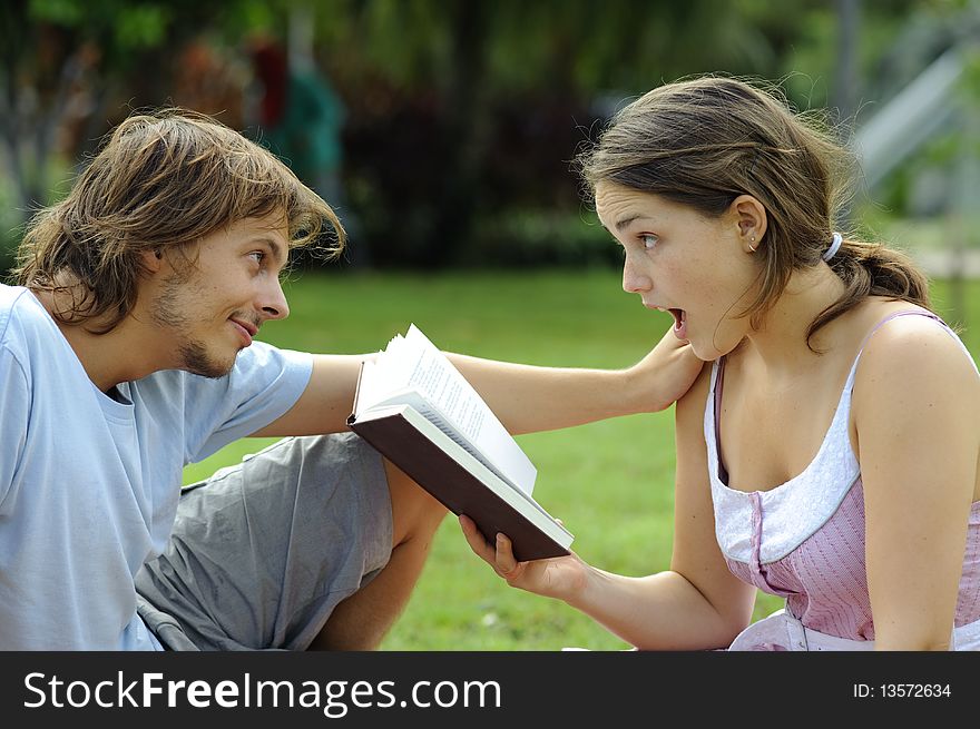 Attractive couple read together in the park. Attractive couple read together in the park