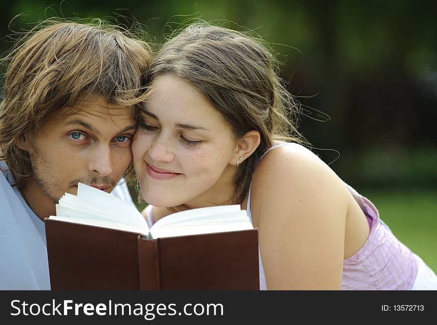 Attractive couple read together in the park. Attractive couple read together in the park