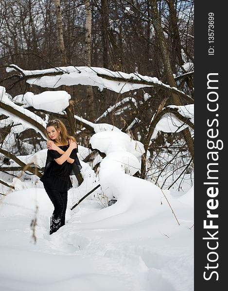Fashion model posing in snowdrift in wood. Fashion model posing in snowdrift in wood