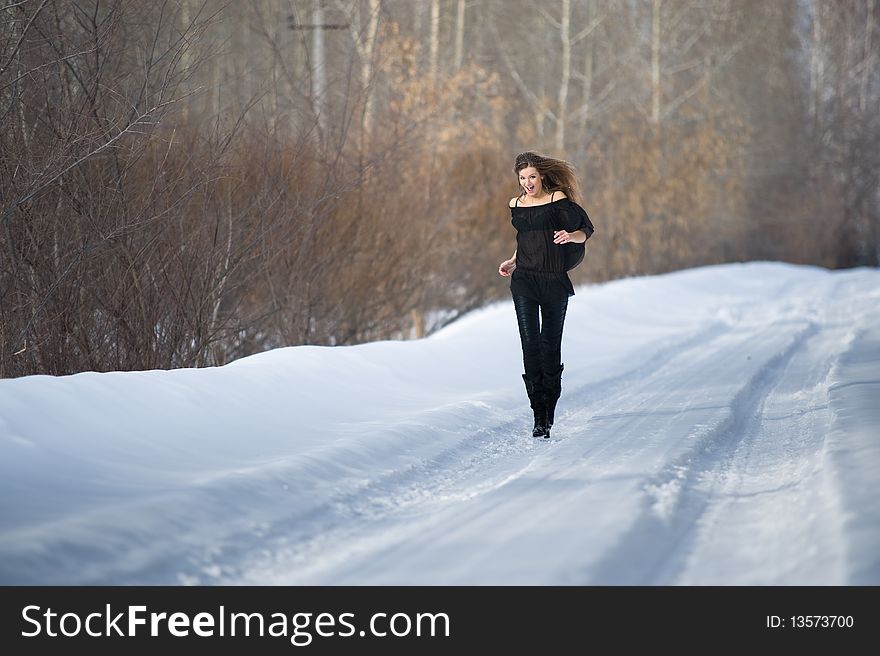 Young beautiful girl runs in wood in winter