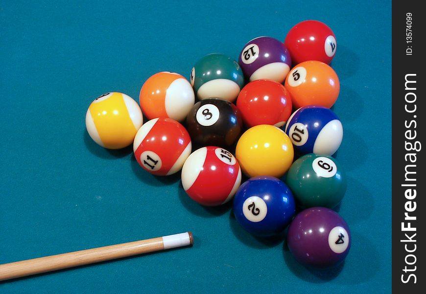 Billiard balls on green table with cue