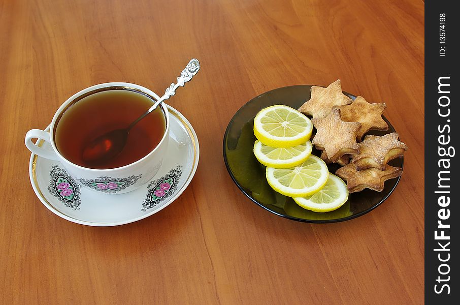 Teacup and homemade cookies with slices of lemon on plate. Teacup and homemade cookies with slices of lemon on plate