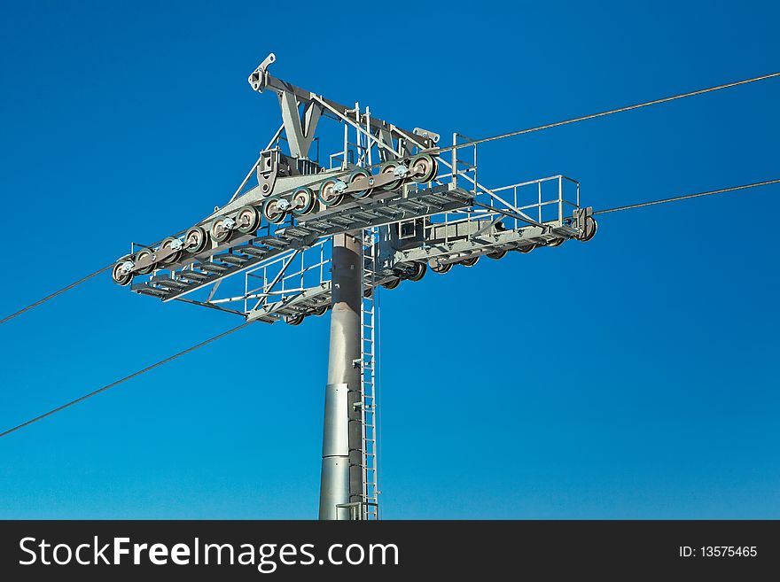 Ski lift pole with support rolls and lines over blue sky. Ski lift pole with support rolls and lines over blue sky.