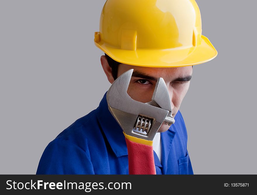 Engineer wearing blue overhauls and yellow hardhat.Looking throught a adjustable wrench. Engineer wearing blue overhauls and yellow hardhat.Looking throught a adjustable wrench.