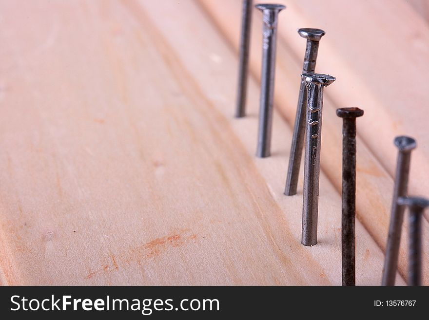 Nails are hammered on one line into a wooden board.