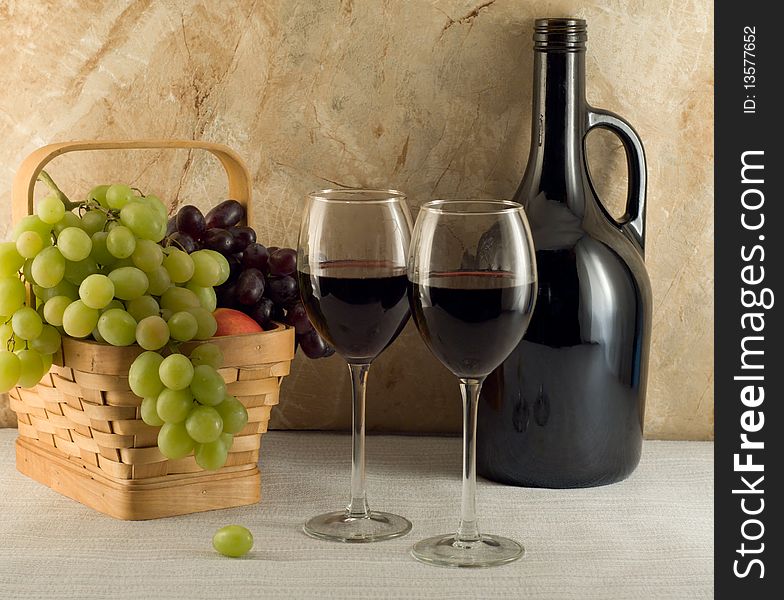 Two glasses of red wine and grapes in a basket. Two glasses of red wine and grapes in a basket