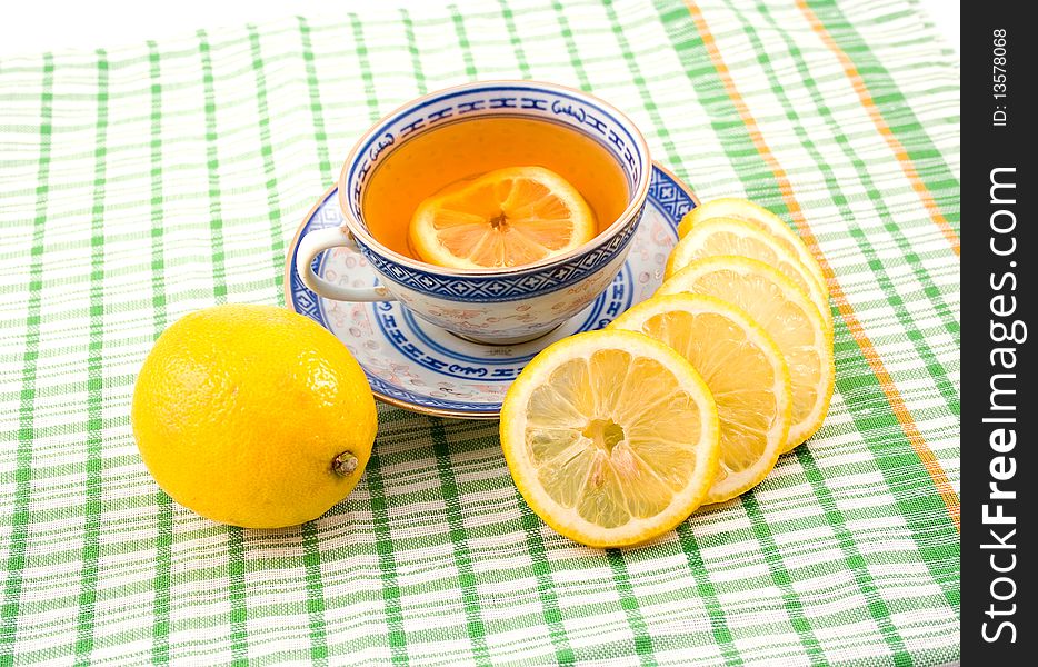 Fragrant tasty useful tea with lemon cup with blue figure on napkin green strip. Fragrant tasty useful tea with lemon cup with blue figure on napkin green strip