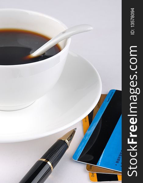 A cup of coffee and a ball pen with credit cards, means drinking, working, signature and relax. A cup of coffee and a ball pen with credit cards, means drinking, working, signature and relax.