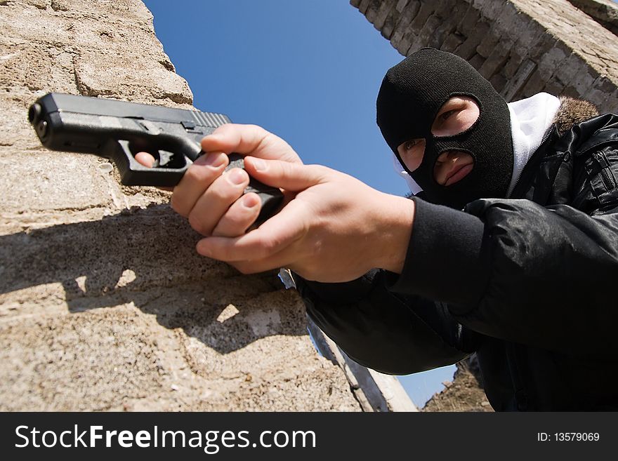 Criminal in black mask aiming his target with a pistol. Criminal in black mask aiming his target with a pistol