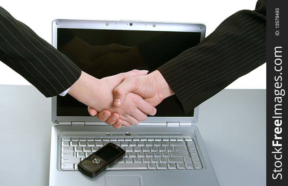 Man and woman shaking hands in front of computer and phone