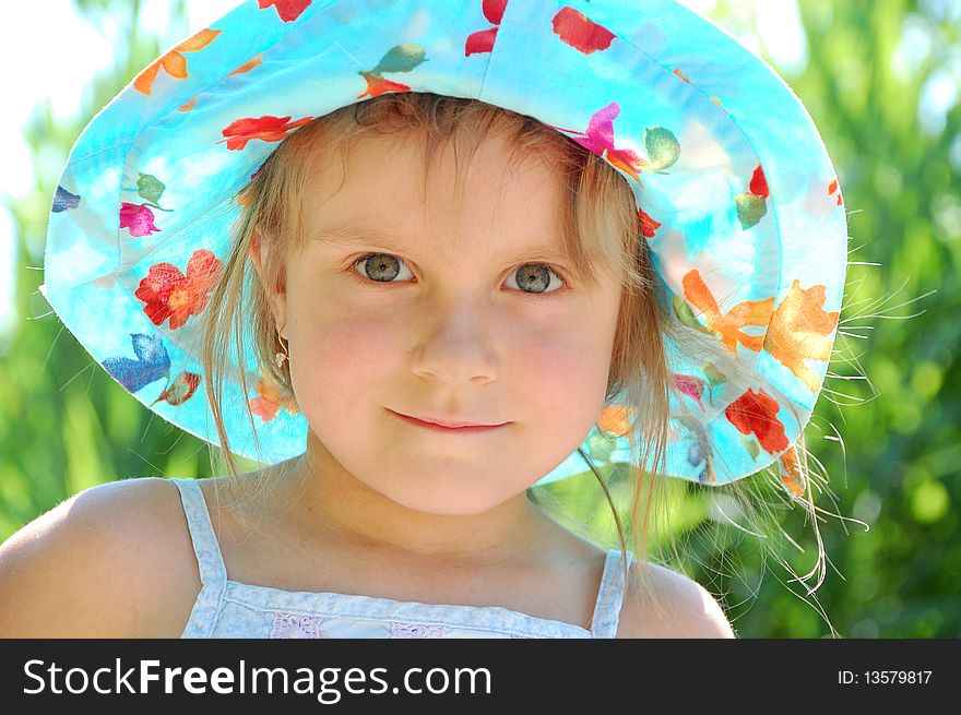 Little girl with a blue hat outdoor on a sunny summer day. Little girl with a blue hat outdoor on a sunny summer day