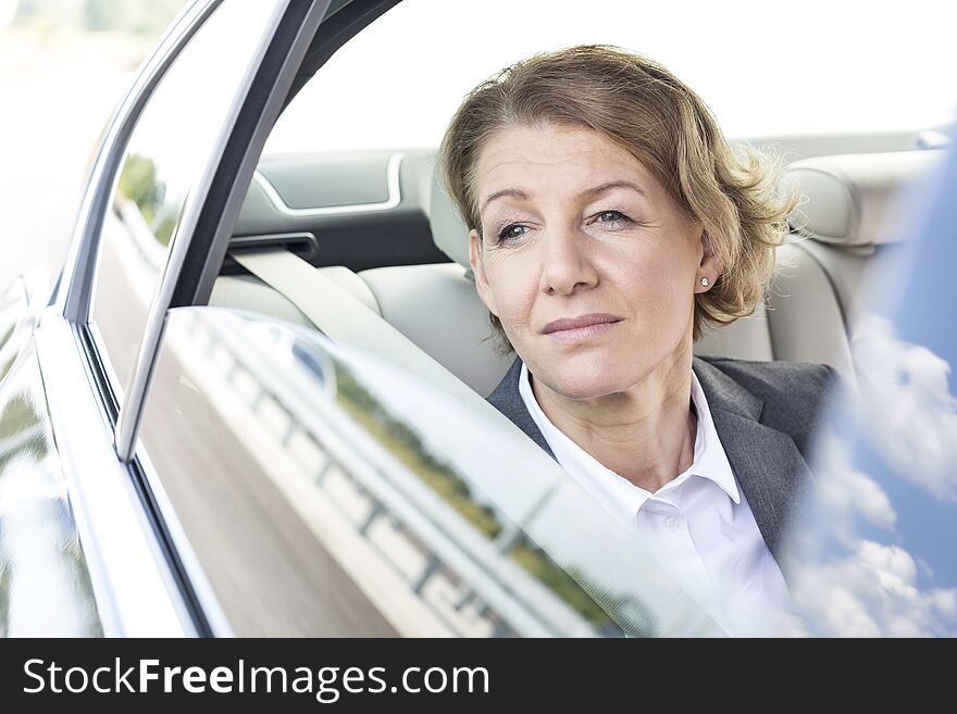 Thoughtful businesswoman looking through window while sitting in car