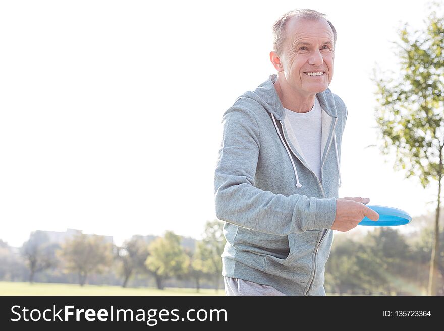 Smiling senior man throwing disc in park