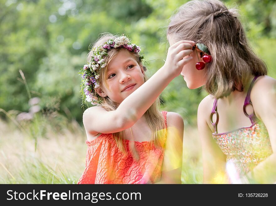 Cute girl holding cherry fruits on friend`s ear at par