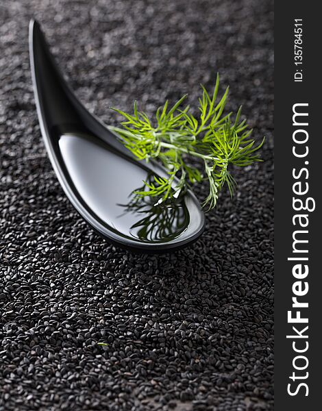 Plant oil with dill branches on a background of black sesame