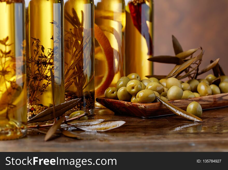 Green olives and bottles of olive oil with spices and herbs