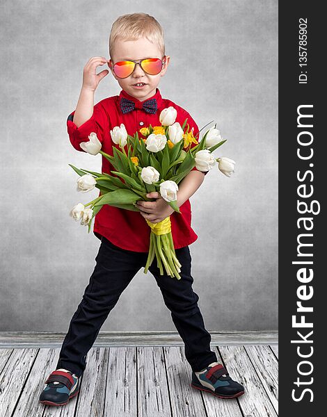 Stylish little boy holds a bouquet of spring tulips.Spring,holiday,children`s fashion.