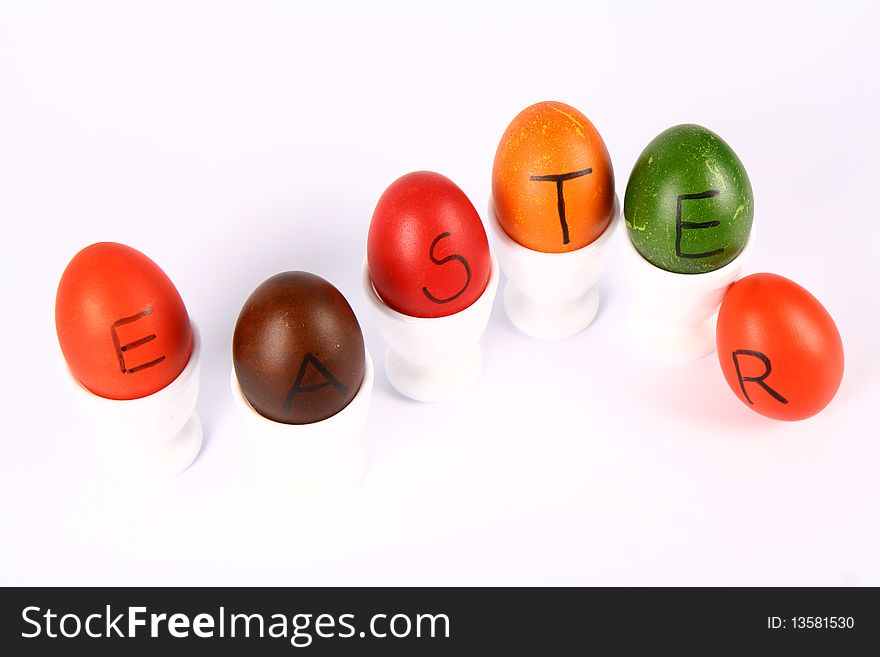 Colorful eggs with the word 'EASTER' written on them in egg holders. Colorful eggs with the word 'EASTER' written on them in egg holders