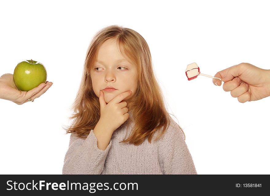 Young girl choosing between an apple and candy