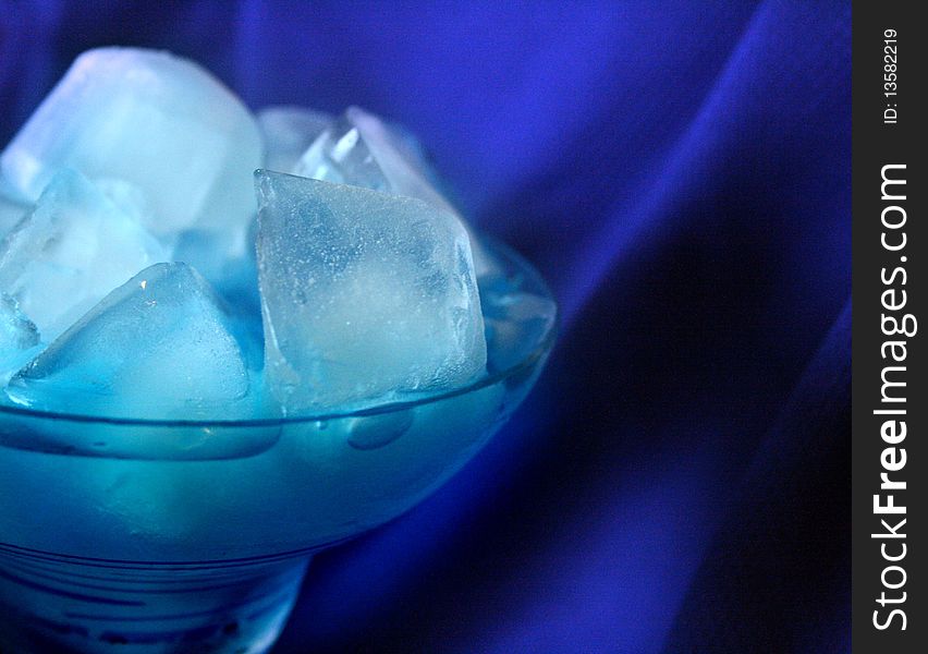 Blue drink in margarita glass full of ice cubes on blue background. Blue drink in margarita glass full of ice cubes on blue background