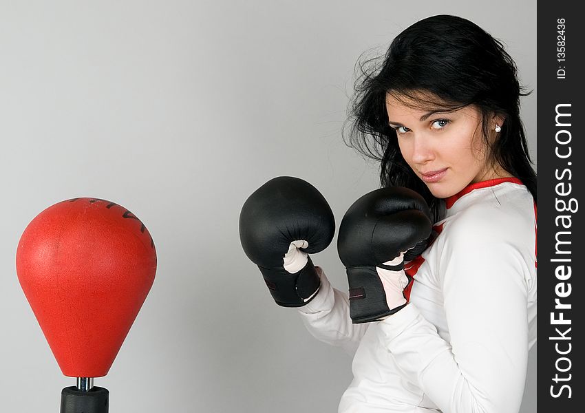 A young woman in boxing gloves hits a punchball