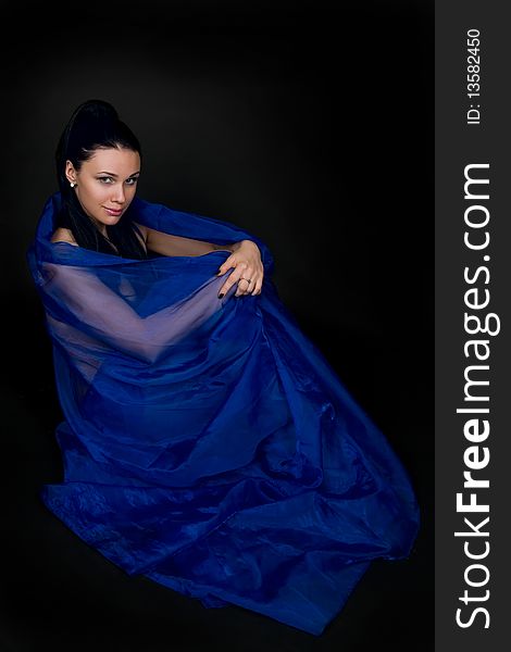 Woman in a transparent dark blue cape on a black background