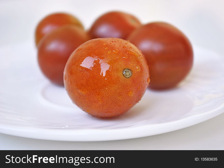 Five cherry tomatoes on white saucer