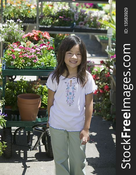 Young Girl Standing In Plant Nursery