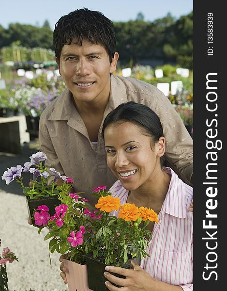 Couple Shopping at Plant Nursery holding flowers, portrait