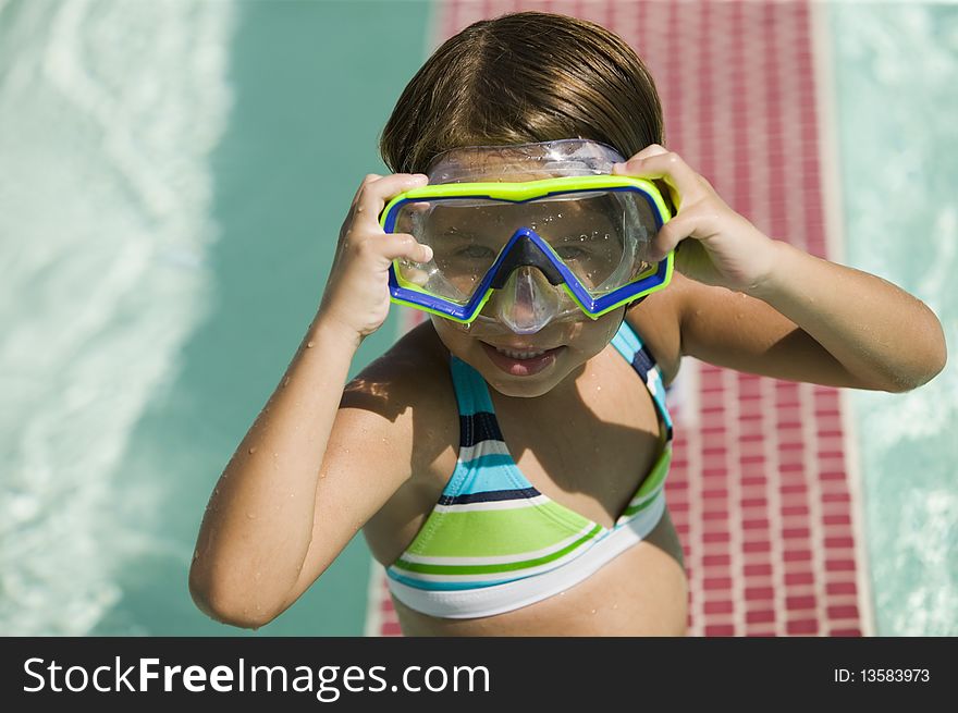 Girl (7-9) Adjusting Goggles in swimming pool, portrait.