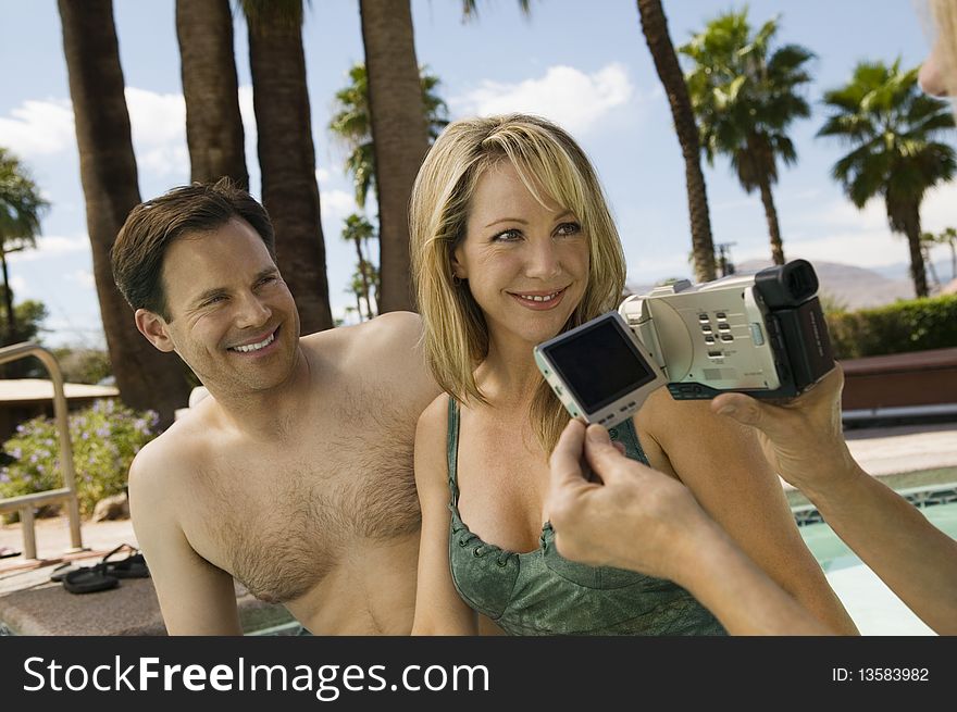 Woman Video Taping Couple by pool.