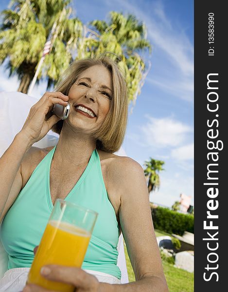 Woman holding glass of juice, using mobile phone, outdoors. Woman holding glass of juice, using mobile phone, outdoors.