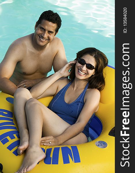 Couple in swimming pool, woman lying on inflatable raft, elevated view portrait.