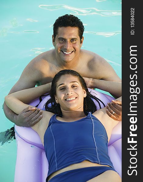 Couple in Swimming Pool, woman lying on inflatable raft, elevated view portrait.