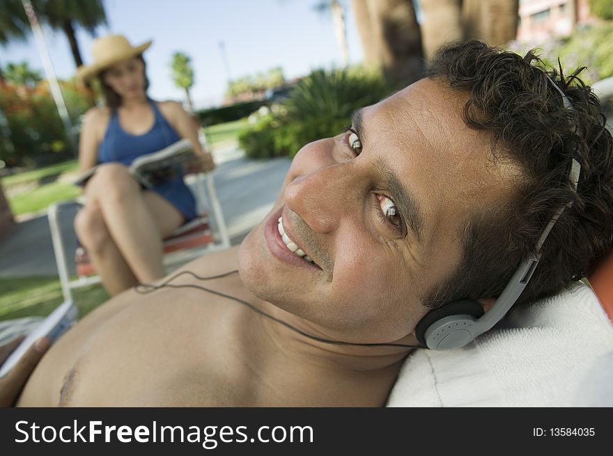 Man Lying on sunlounger Listening to headphones, portrait. Man Lying on sunlounger Listening to headphones, portrait.