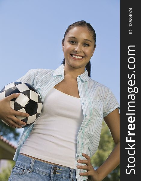 Young Woman Holding Soccer Ball, low angle view.