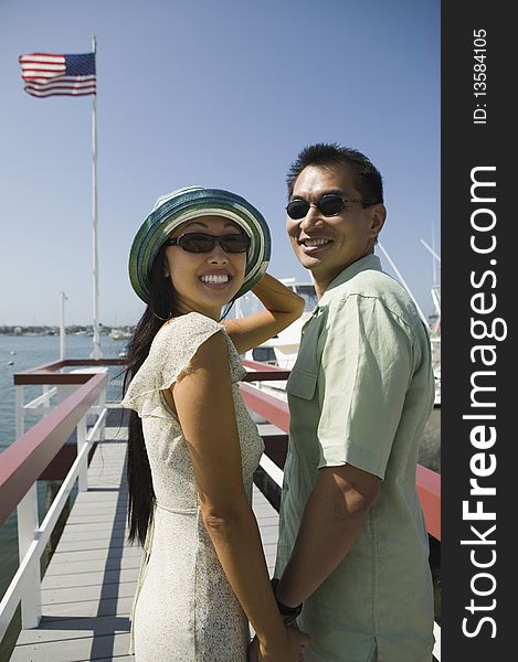 Couple standing on pier, (portrait). Couple standing on pier, (portrait)