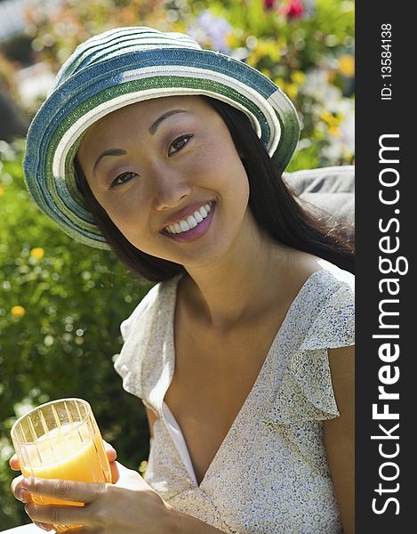 Woman drinking orange juice, outdoors, (portrait)