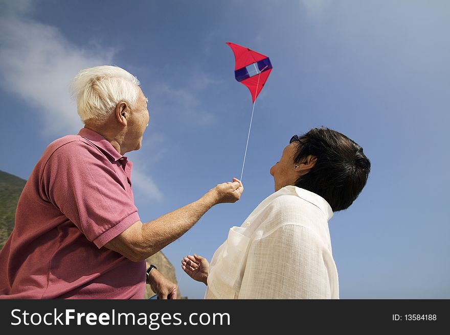 Couple flying kite outdoors, (low angle view)