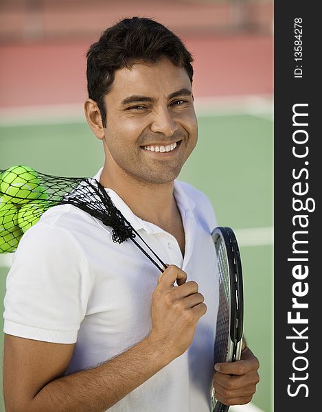 Man on tennis court with tennis balls and racket