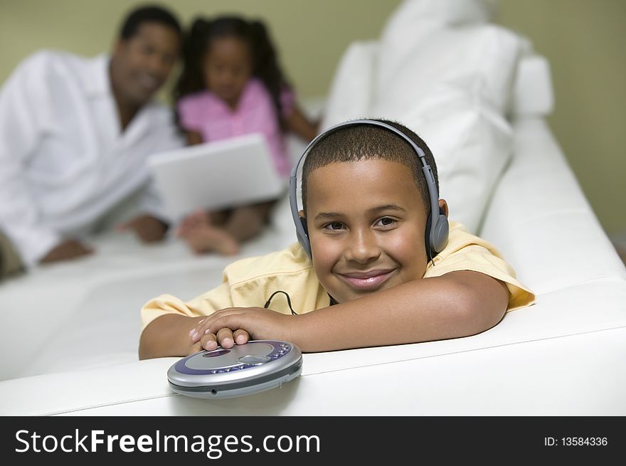 Boy Listening To Music, Father And Sister On Sofa