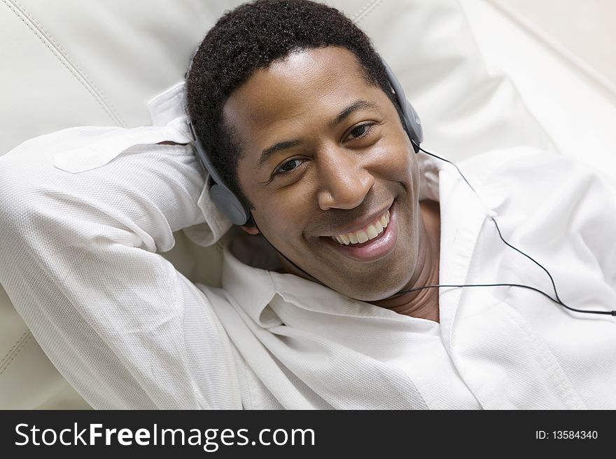 Man lying on sofa Listening to Music on portable CD player, portrait, overhead view