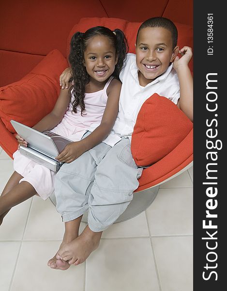 Brother And Sister In Chair With DVD Player