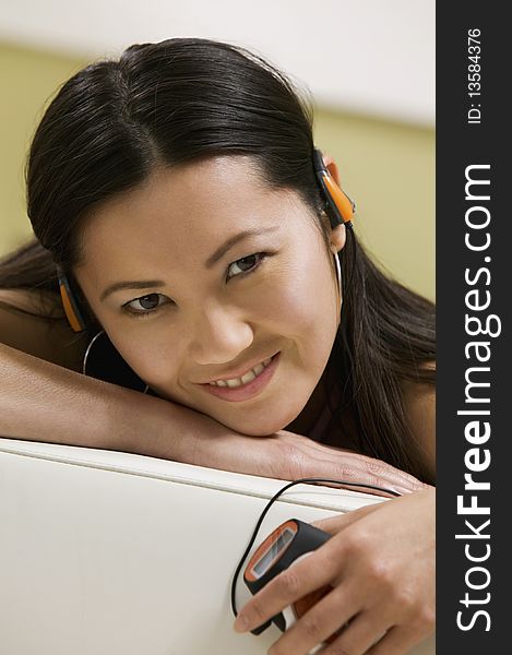 Young Woman lying on sofa Listening to MP3 Player, portrait, close up. Young Woman lying on sofa Listening to MP3 Player, portrait, close up